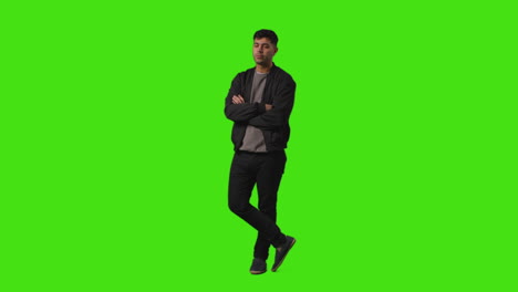 Full-Length-Shot-Of-Fed-Up-Casually-Dressed-Young-Man-Standing-Against-Green-Screen-Folding-Arms-And-Putting-Hands-In-Pockets-2