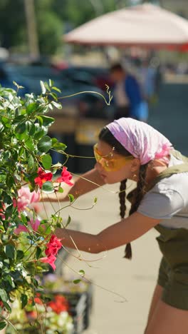 mujer regando flores en un mercado