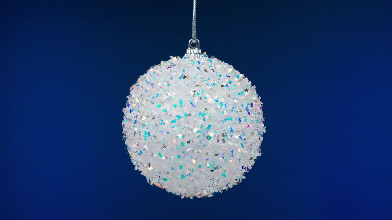 Funkelnder weißer Glitzer-Weihnachtsschmuck auf blauem Hintergrund