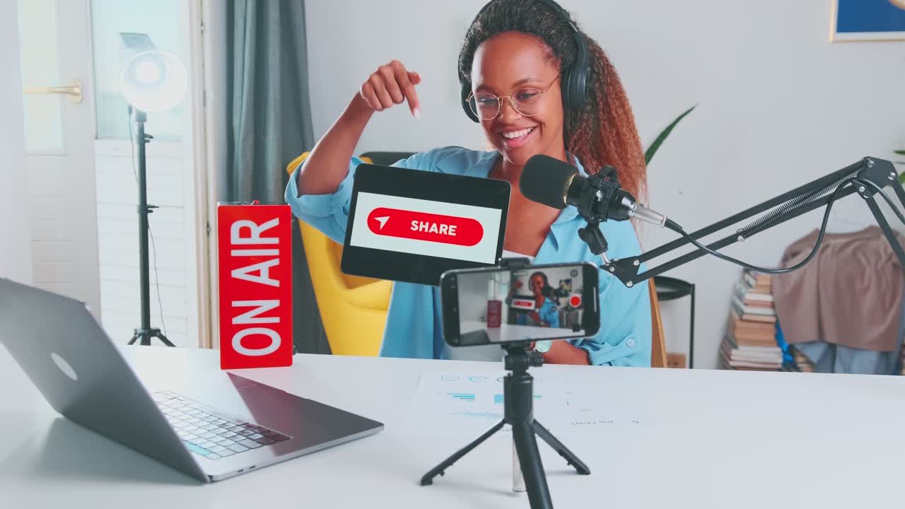 Young smiling african american woman streamer holding tablet with share button