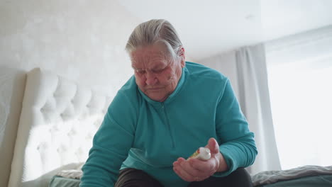old woman in green sitting on bed, applying ointment to her foot with a pained expression. soft light filters through the window, creating a calming atmosphere as she takes care of her health