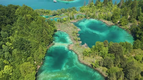 top view of the plitvice lakes national park with many green plants, beautiful lakes and a boat sailing in these lakes