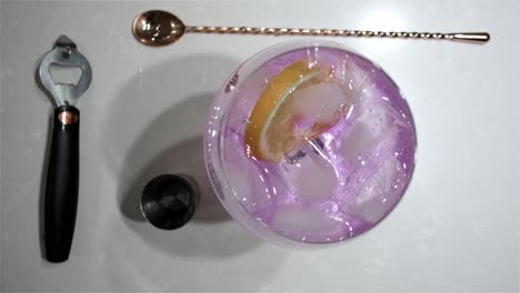 top view of a large stemmed balloon glass as the slice of orange is added as a final touch to a delicious pink gin and tonic cocktail