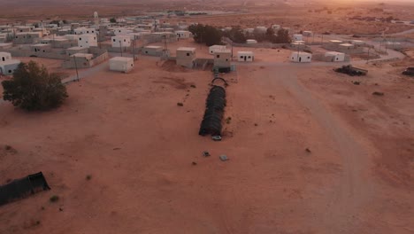 toma aérea de un invernadero negro en una antigua ciudad pobre y vacía en el desierto de palestina, cerca de gaza, por la mañana