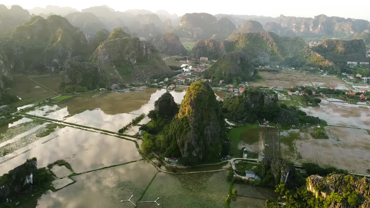 Perbukitan karst batu kapur yang besar di atas sawah yang tergenang air dan tanggul berliku di lanskap Ninh Binh yang indah