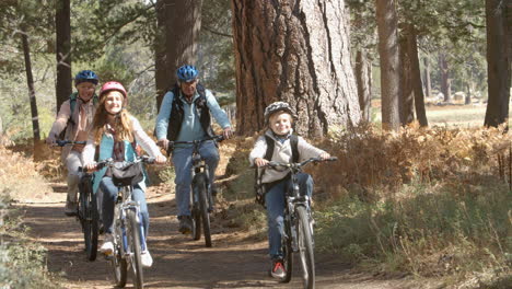 grandparents and kids riding bikes in forest, front view