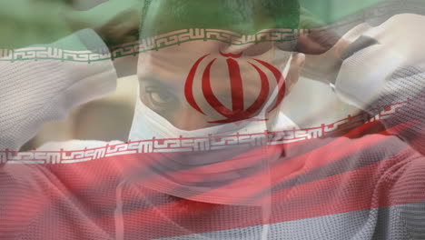 animación de la bandera de irán ondeando sobre un hombre que usa una máscara facial durante la pandemia de covid-19