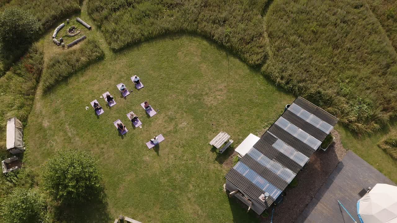 tomada con avión no tripulado del maestro que lidera un grupo de hombres y mujeres maduros en clase en un retiro de yoga al aire libre
