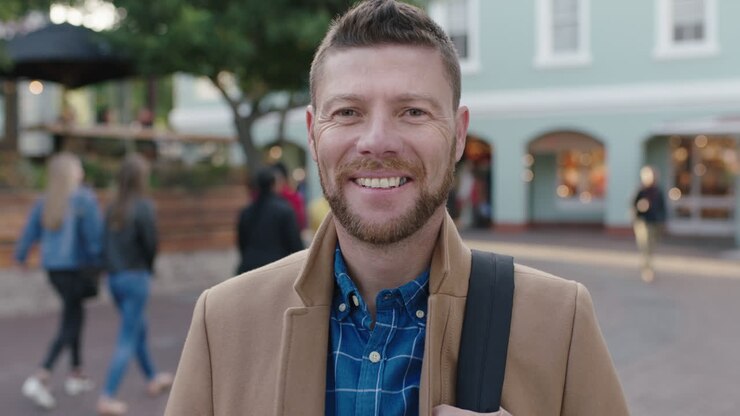 ritratto a rallentatore di un affascinante uomo caucasico che indossa una giacca sorridente felice sullo sfondo urbano