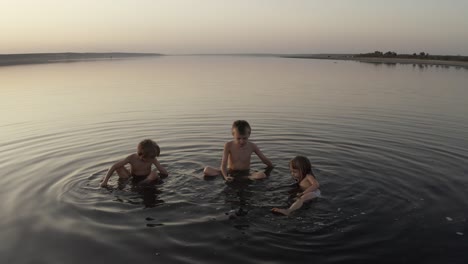 three kids swim and play in the lake