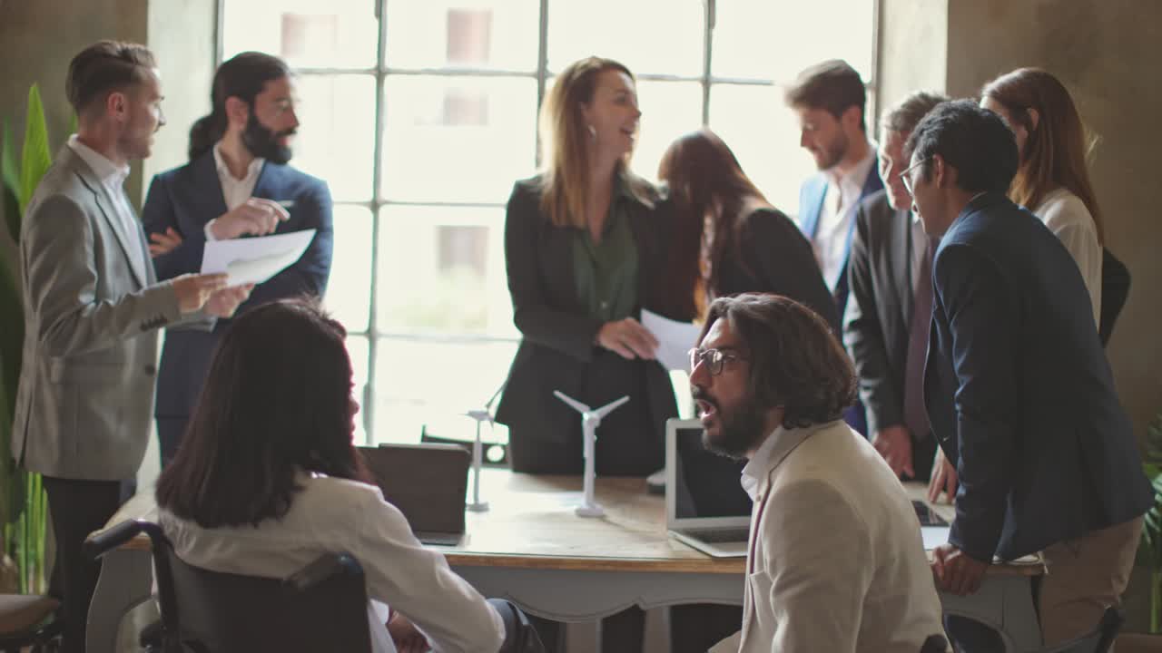african american businesswoman in wheelchair and middle east businessman talking at the business meeting with other colleagues