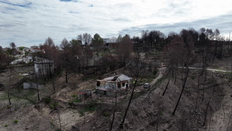 aerial view flying over burnt wreckage of family homes after forest wildfire blaze