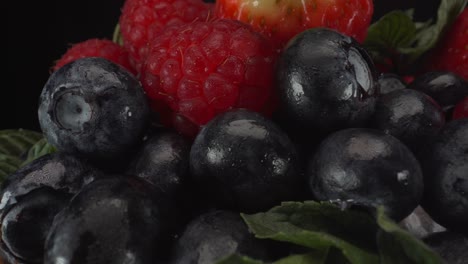 incredibly juicy macro view of rotating forest fruits with black background, strawberries, blueberries, raspberries, healthy fruits, 4k shot