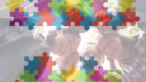 animation of jigsaw puzzle pieces over low angle view diverse children looking down at camera