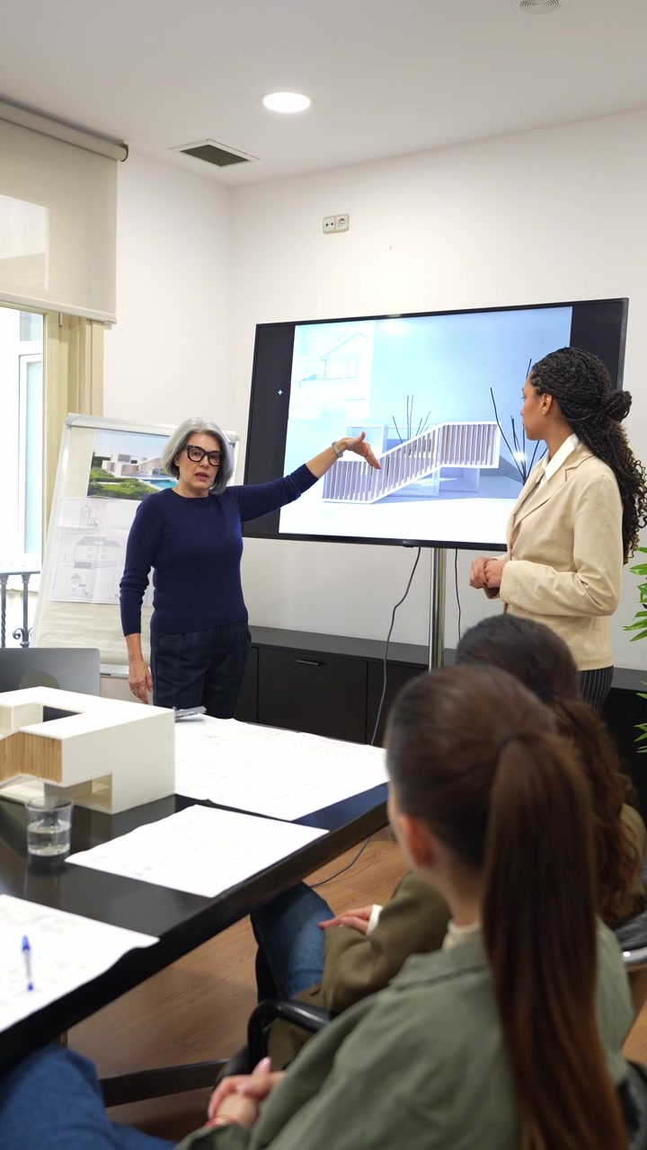 Architetto donna presenta un progetto di edificio moderno agli studenti in ufficio