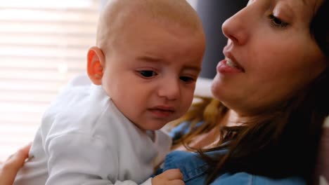 Young-mother-holding-and-kissing-her-baby-at-home-4k