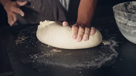 mano del chef preparando masa fresca para cocinar pasteles en la mesa negra, vista de cerca