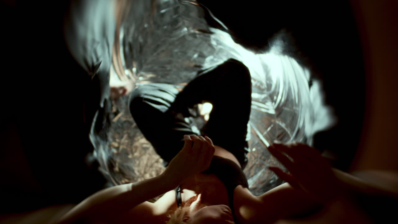 Female Dancer Reaching Out and Gazing Up among Swirling Reflective Surfaces