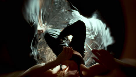 female dancer reaching out and gazing up among swirling reflective surfaces