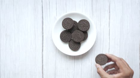 hand holding an oreo cookie from a plate of oreos