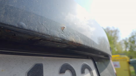 Peeling-Car-Paint-on-Black-Car-with-Bubbles-Underneath-Due-to-Rust,-Close-Up-on-Public-Street