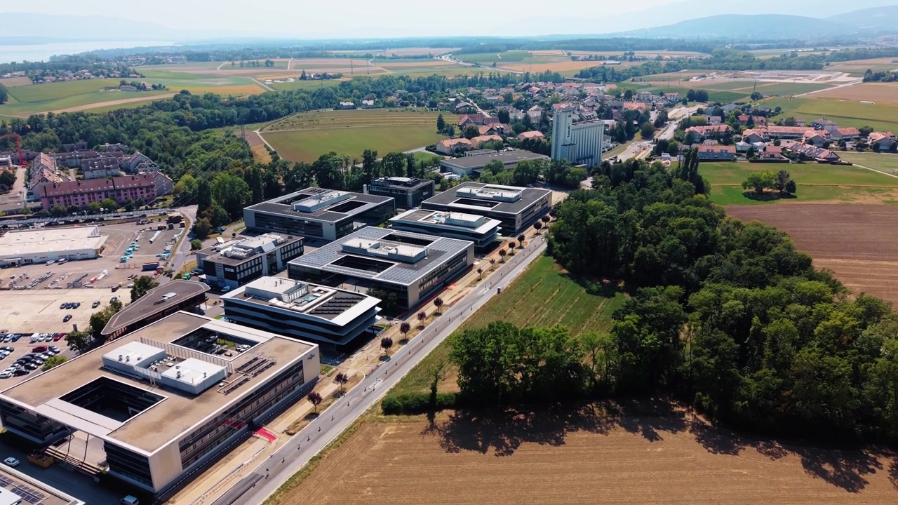 Campi verdi si estendono accanto al parco commerciale a Nyon, Svizzera, drone in discesa verticale
