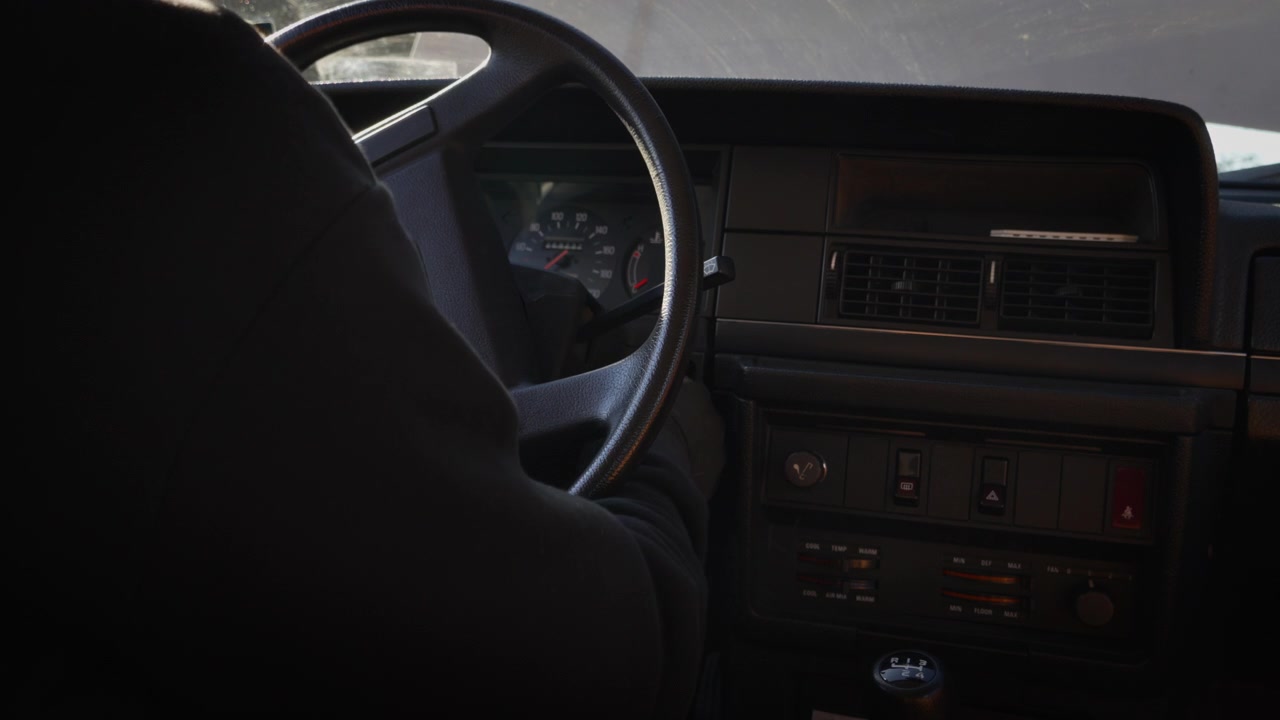 Una persona entra e avvia una vecchia auto, mostrando gli interni vintage, il volante e il cambio manuale. Ideale per contenuti su veicoli classici, guida e stile di vita automobilistico.