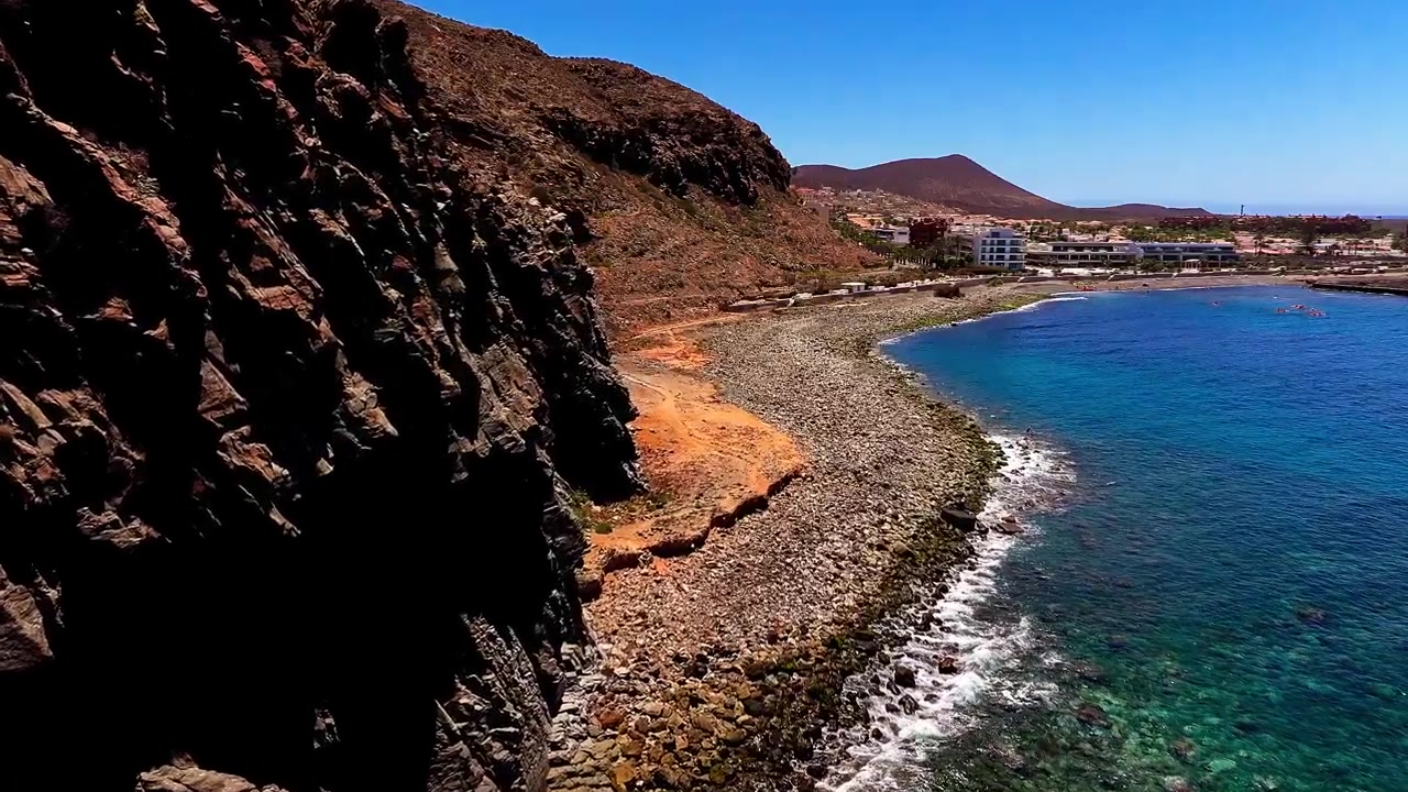 Vista aérea con dron de aguas costeras que se encuentran con la escarpada costa rocosa y el terreno volcánico en Punta del Bocinegro en Tenerife, Islas Canarias. Naturaleza costera.