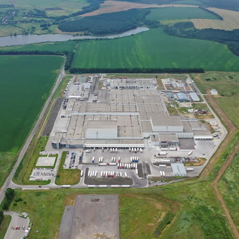 aerial view of manufacturing area surrounded by green fields. top view of industrial complex with parking place on natural background.