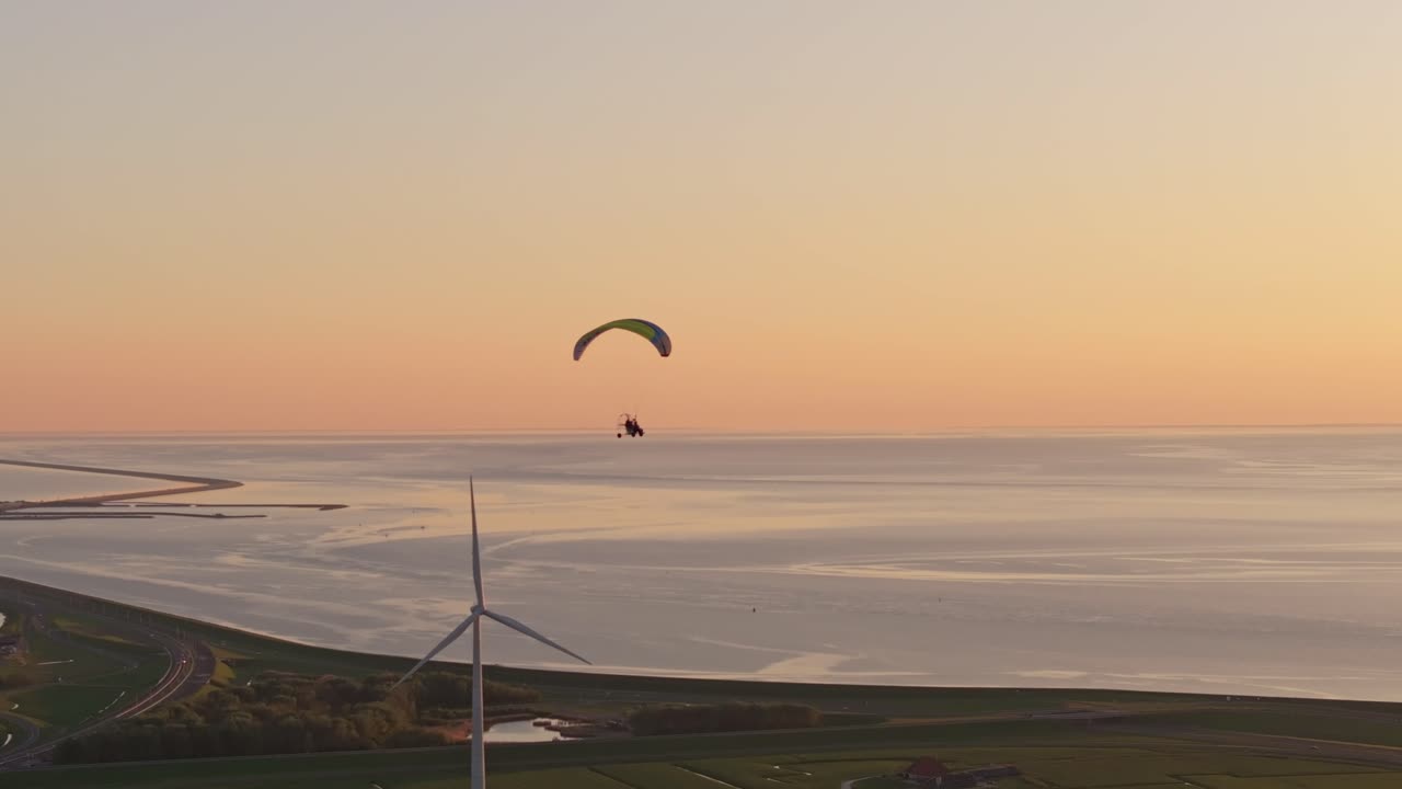 Aerial view of paramotor flight during scenic sunset across Dutch fields