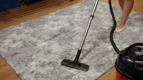 a woman vacuuming a grey rug