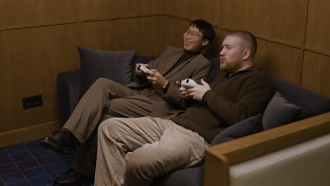 two men playing video games on couch