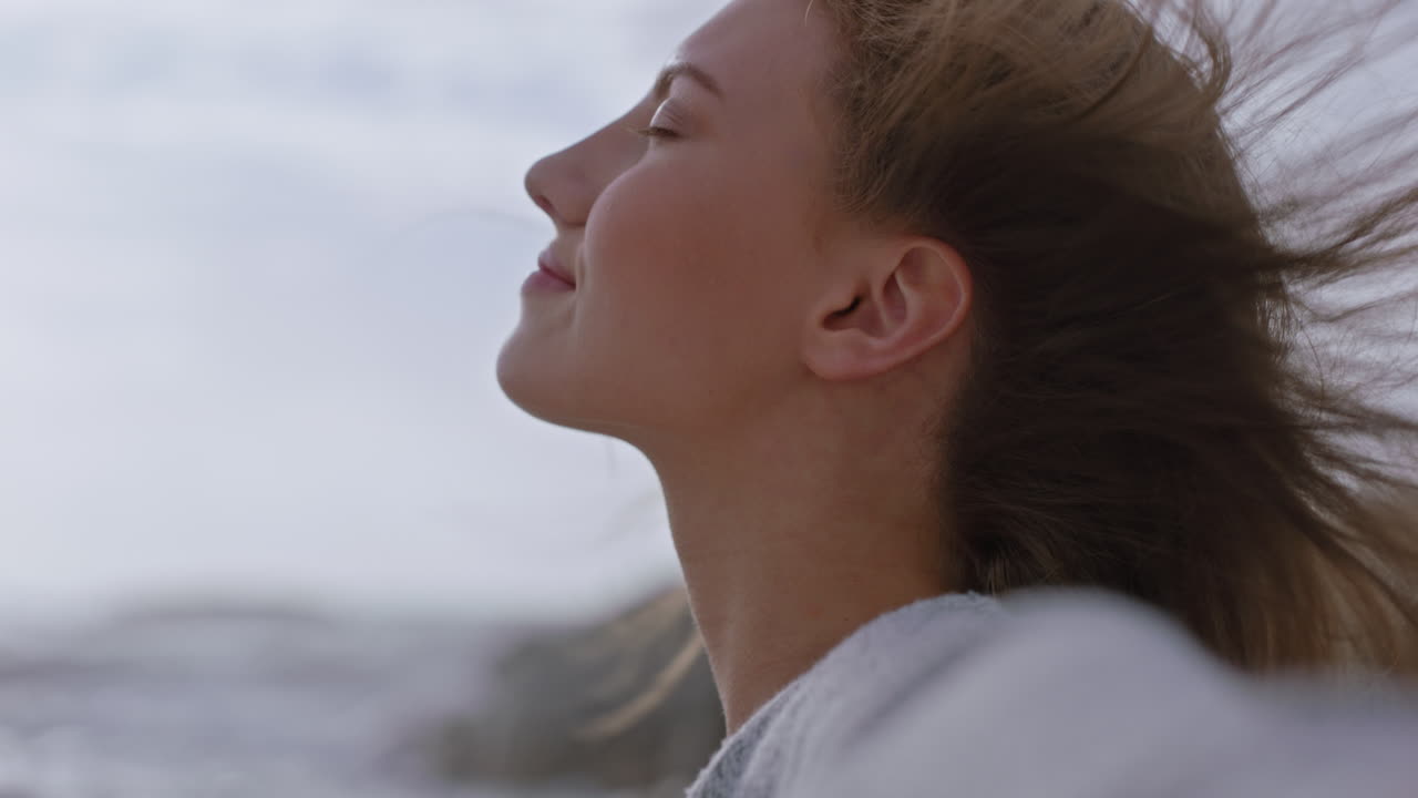retrato de cerca de una mujer hermosa sonriendo disfrutando de la playa relajándose en la orilla del mar el viento soplando el cabello explorando un estilo de vida tranquilo y despreocupado