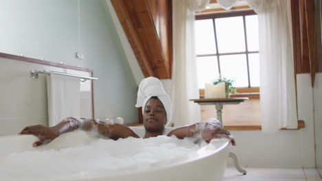 african american attractive woman relaxing in foam bath in bathroom