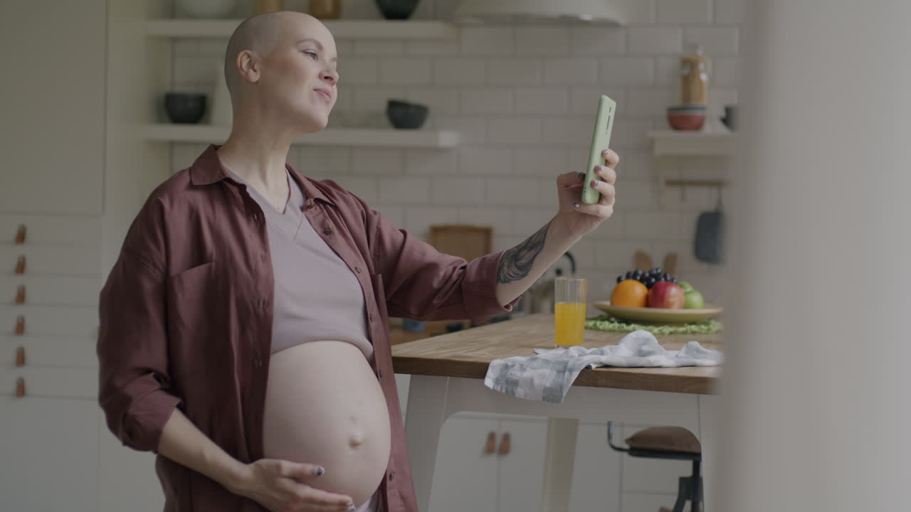 Femme enceinte prenant un selfie dans la cuisine