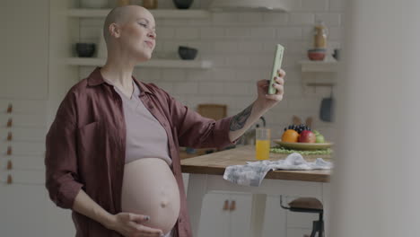 pregnant woman taking a selfie in the kitchen