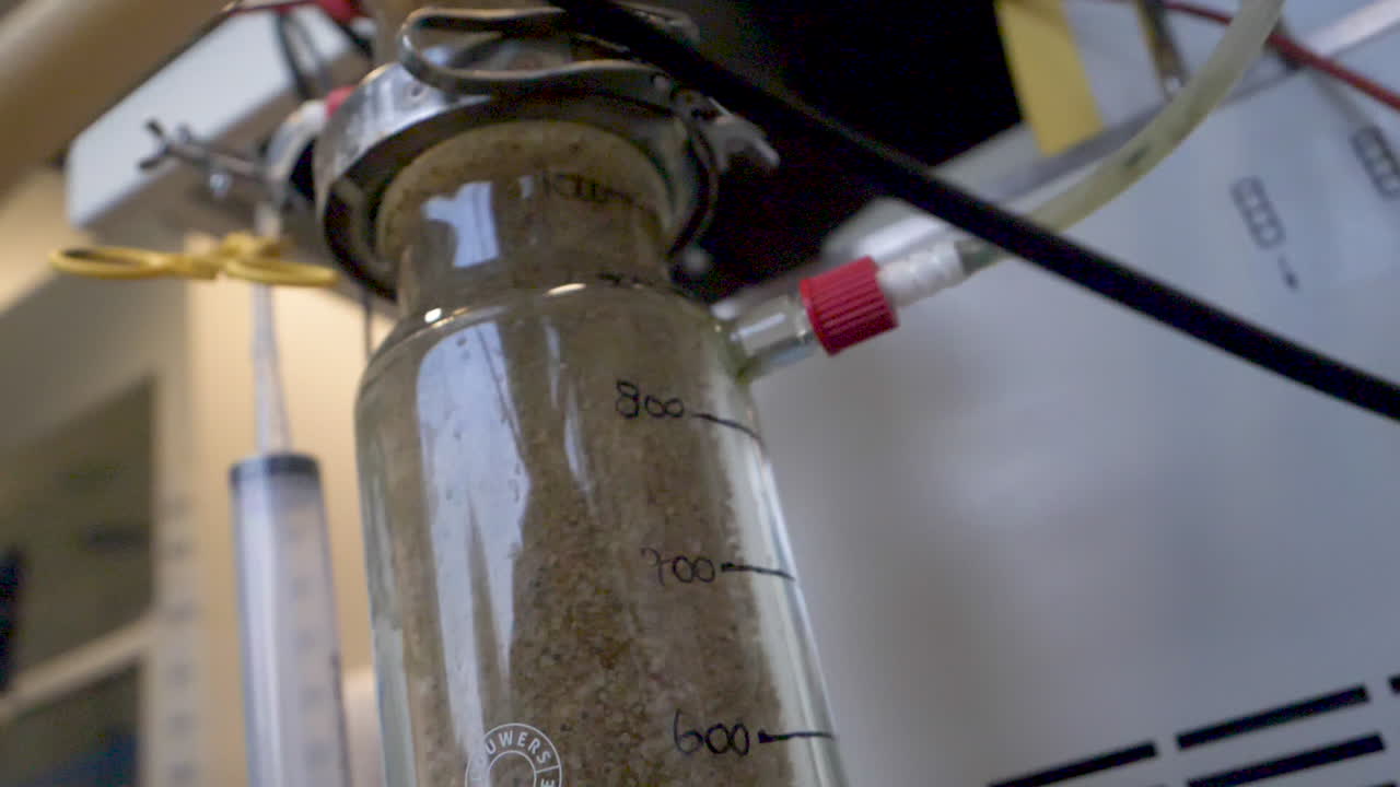 A glass beaker from a wastewater sanitation laboratory separating sand and dirt.