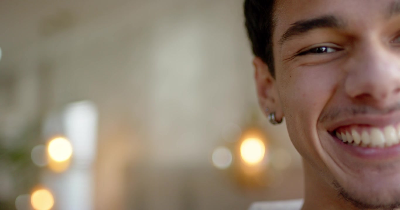 Uomo afroamericano che si appoggia, sorridendo e ridendo a casa, con un orecchino a perno, luci bokeh e spazio per il testo.