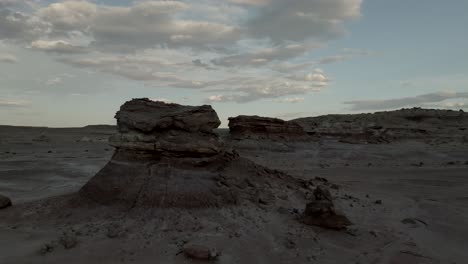 flying by a lone butte in a desert landscape at sunset - aerial flyover