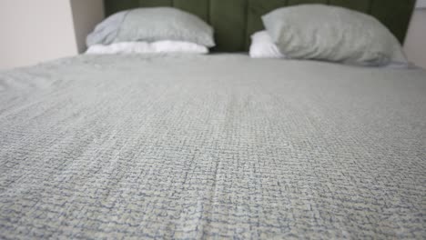 closeup of a made bed with green pillows