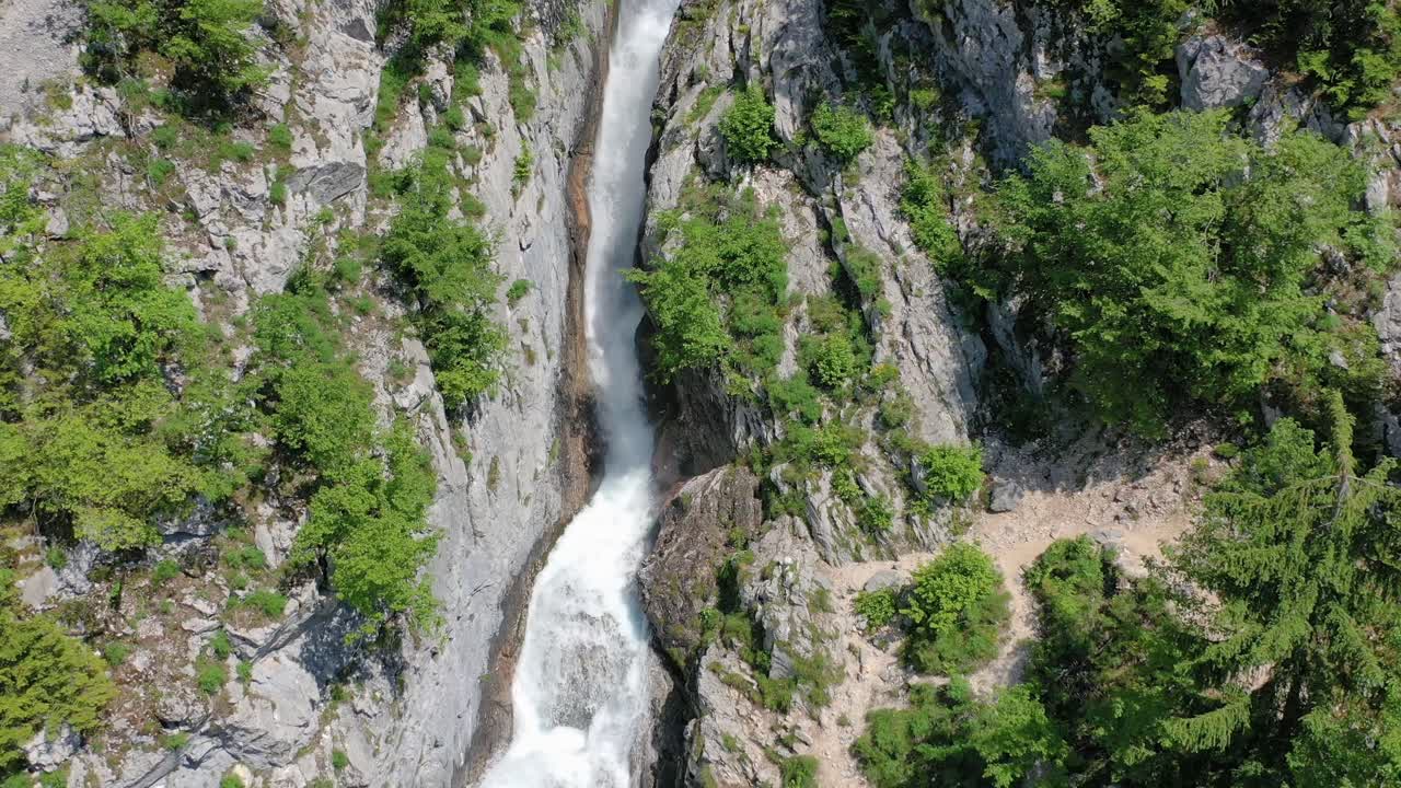 Water rapidly flows down the waterfall. Aerial shot flying backwards. Amazing nature scene. Boka waterfall, Slovenia