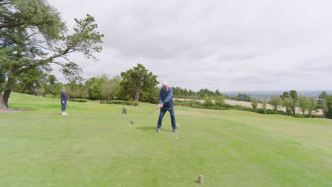 golf players playing golf and knocking golf ball out on golf course on cloudy day, copy space