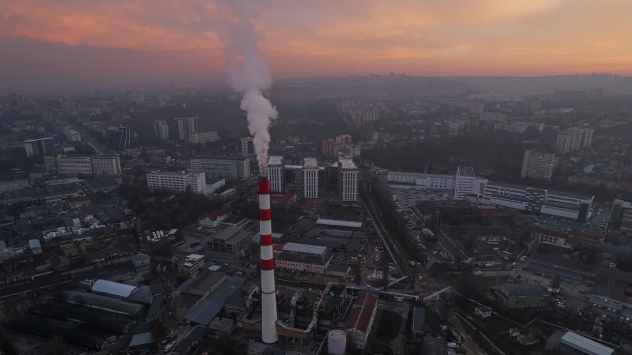 Aerial drone timelapse view of thermal power plant in Chisinau at sunset, Moldova. View of pipe with felling steam, cityscape