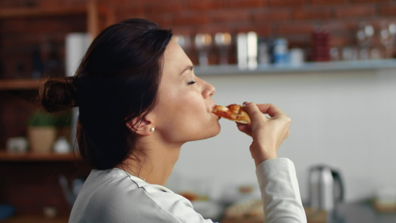 mujer mirando a la cámara con una pieza de pizza. niña hambrienta comiendo pizza y patata
