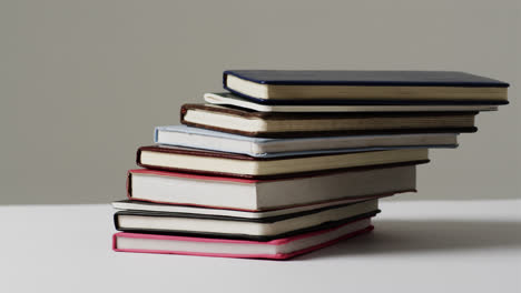 Close-up-of-stack-of-books-on-grey-background,-in-slow-motion