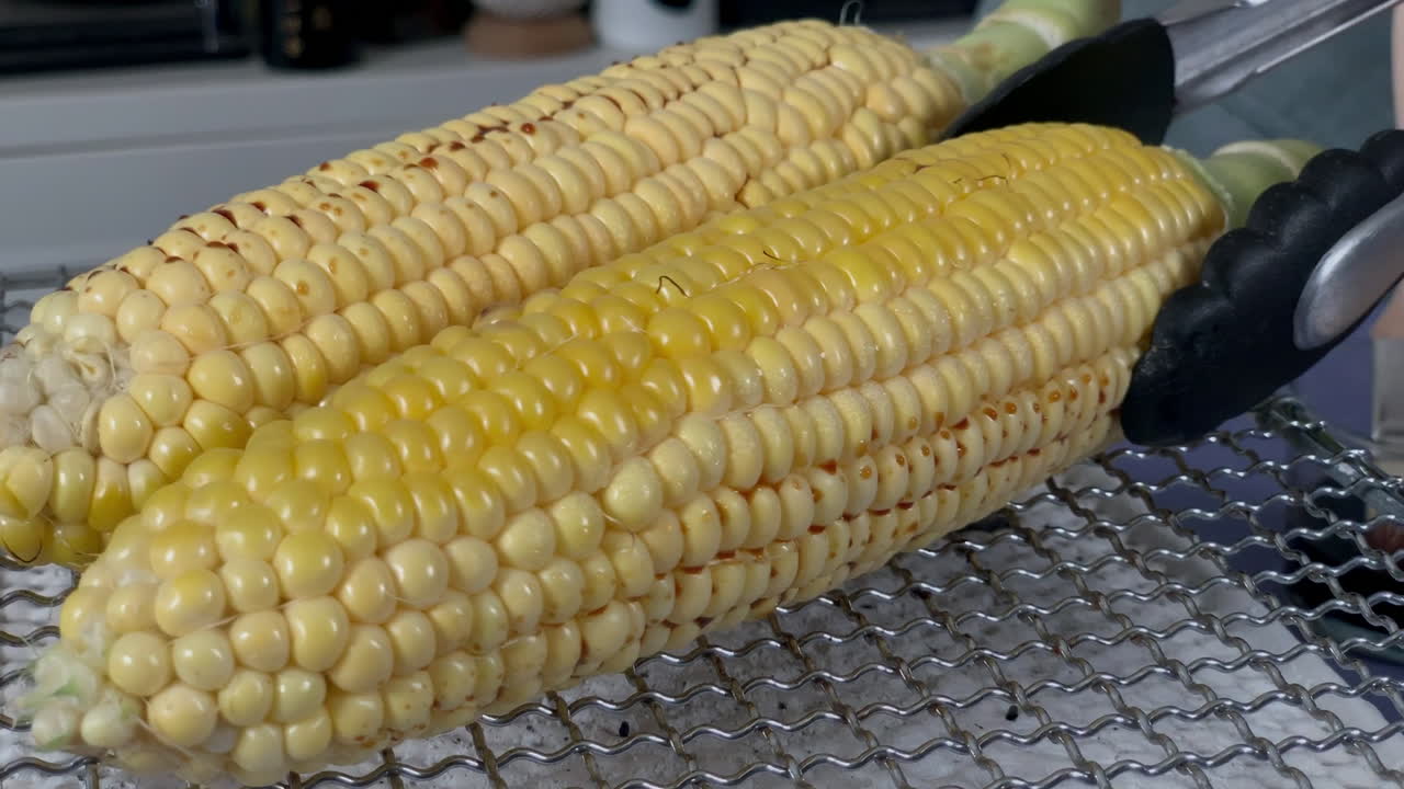 una chef japonesa pone shoyu en maíz a la parrilla en la cocina de su casa, tokio, japón