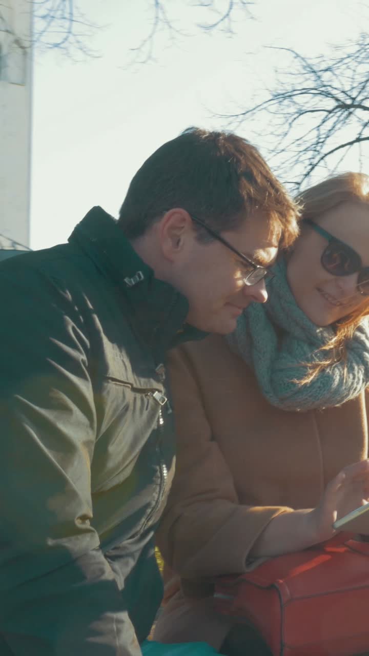 Casal olhando para um celular em um parque