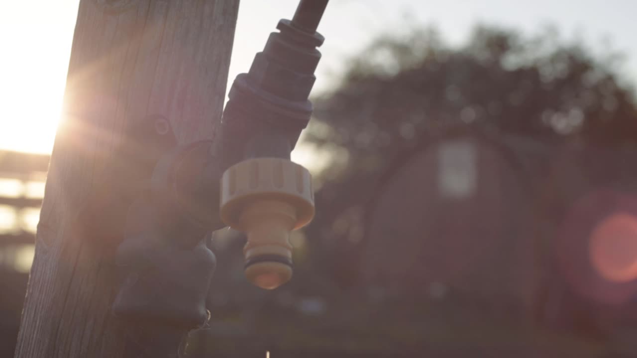 Dripping faucet tap in garden against sunset close up shot