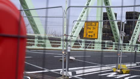 covid social distancing metal sign on empty closed runcorn jubilee bridge mesh fence left dolly fencing closeup