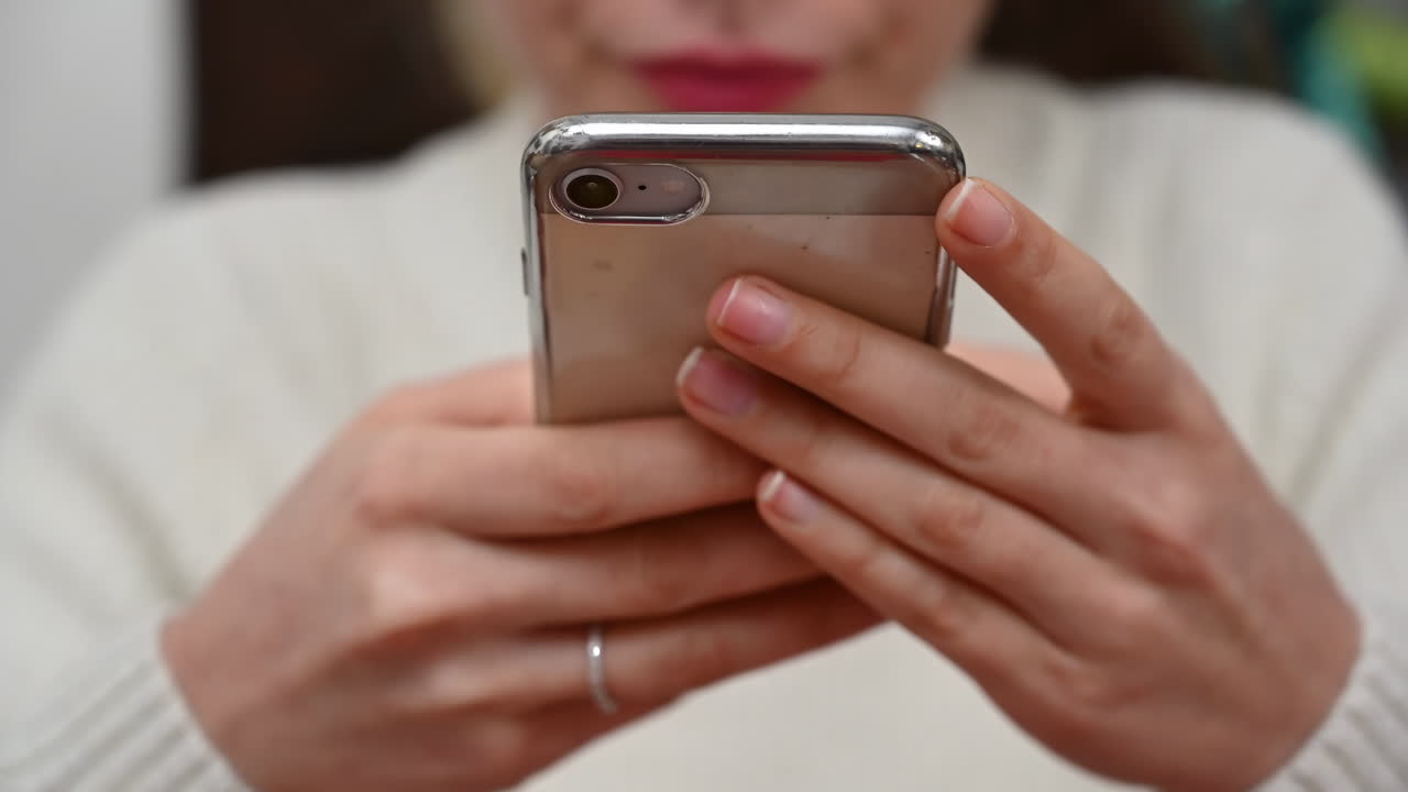 Close up of a brunette woman in a white turtleneck scrolling through her phone